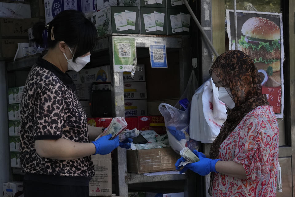 Vendors exchange Chinese yuan notes at a store on Sunday, July 17, 2022, in Beijing. China's yuan fell to a 14-year low against the dollar Wednesday, Sept. 28, 2022, despite central bank efforts to stem the slide after U.S. interest rate hikes prompted traders to convert money into dollars in search of higher returns. (AP Photo/Ng Han Guan)