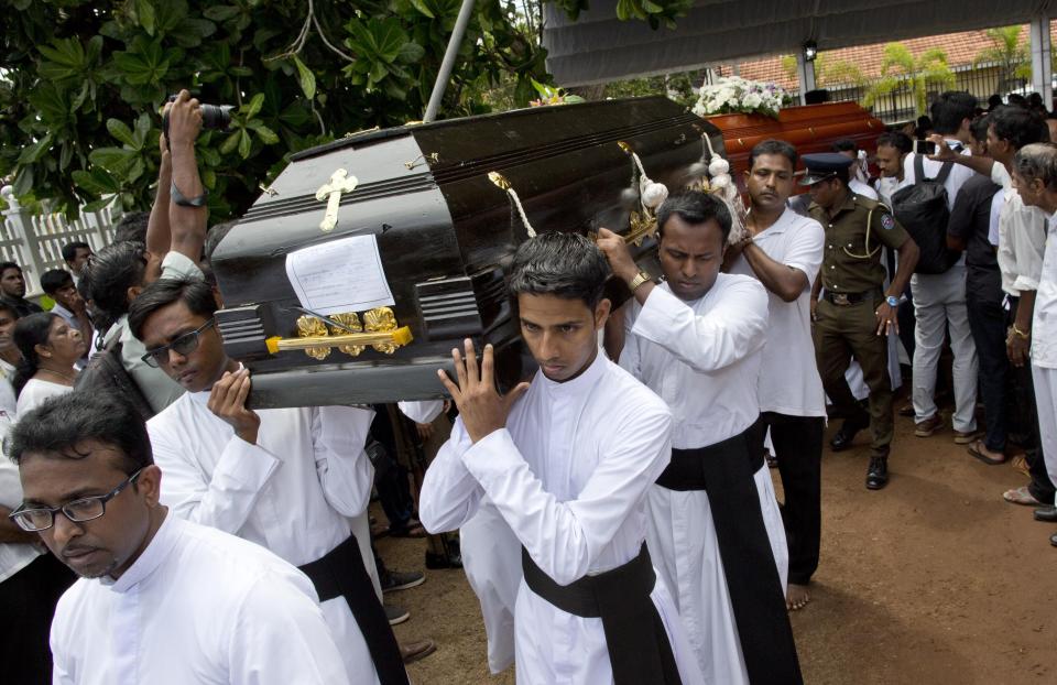 Clergymen carry coffins for burial during a funeral service for Easter Sunday bomb blast victims at St. Sebastian Church in Negombo, Sri Lanka, Tuesday, April 23, 2019. (AP Photo/Gemunu Amarasinghe)