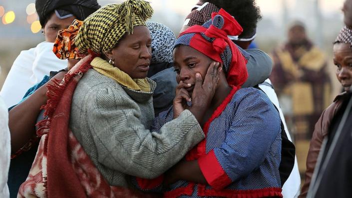 Women mourn as family members of the 34 people who died when police opened fire on strikers at the Lonmin platinum mine north west of Johannesburg on August 16, 2013 gather at the scene of the bloody shooting to cleanse the ground