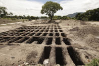 Freshly dug graves expand across a section of La Bermeja General Cemetery to meet the demands of the increase in deaths related to the new coronavirus, in San Salvador, El Salvador, Friday, Aug. 7, 2020. For months, the strictest measures confronting the COVID-19 pandemic in Latin America seemed to keep infections in check in El Salvador, but a gradual reopening combined with a political stalemate has seen infections increase nearly fourfold. (AP Photo/Salvador Melendez)