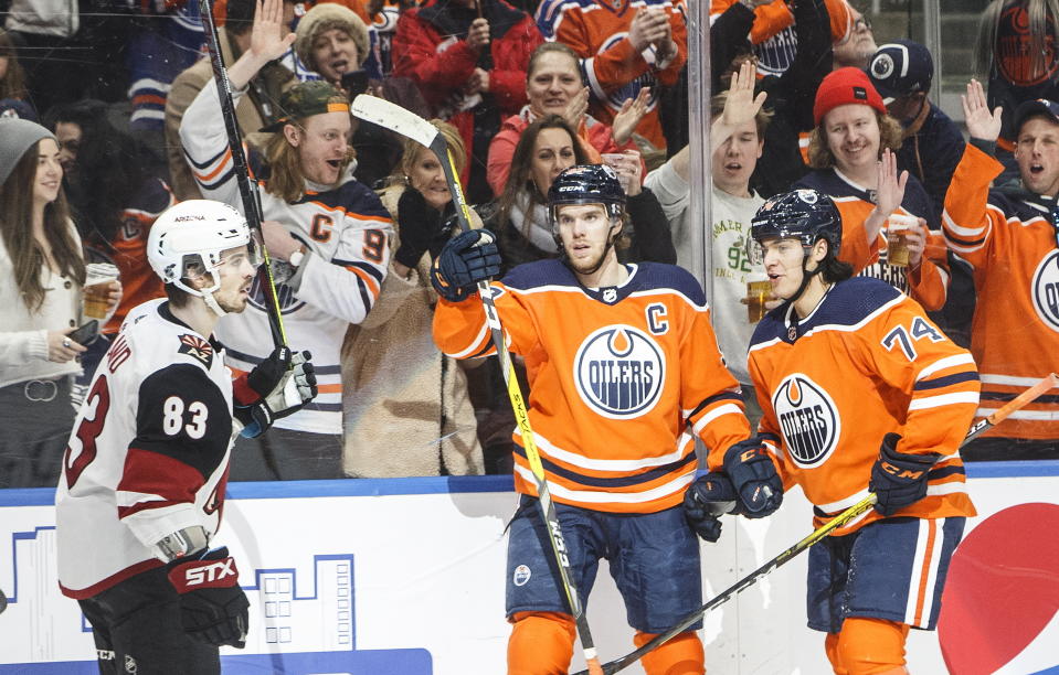 Arizona Coyotes' Conor Garland (83) skates past as Edmonton Oilers' Connor McDavid (97) and Ethan Bear (74) celebrate a goal during second period NHL action in Edmonton, Alberta, on Saturday, Jan. 18, 2020. (Jason Franson/The Canadian Press via AP)