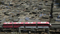 FILE - A Mumbai Monorail train moves past a slum area during a trial run between Wadala and Chembur in Mumbai, India, on Jan. 30, 2014. (AP Photo/Rajanish Kakade, File)