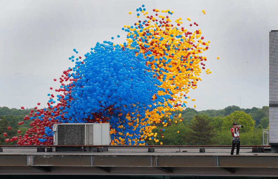 IMS photographer Chris Jones stands on the top of the media center as the balloons are released behind him before the start of the Indianapolis 500 at Indianapolis Motor Speedway on Sunday, May 26, 2019.