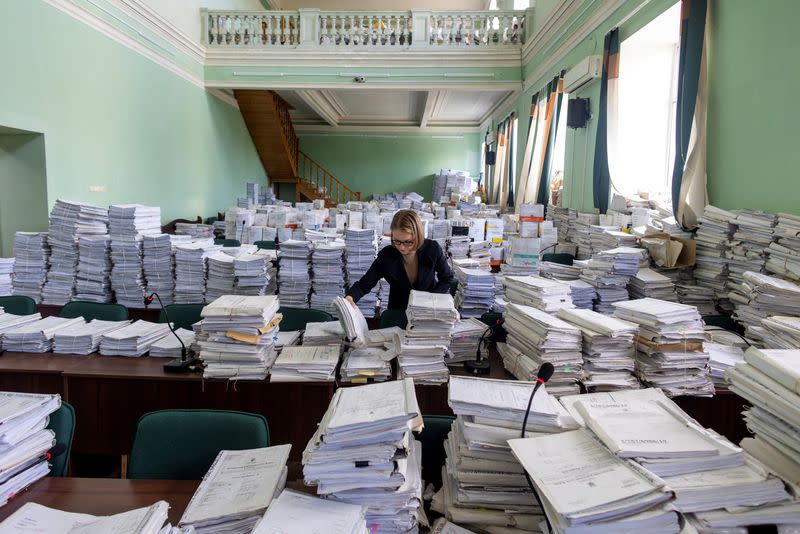 An employee looks through court documents in a former court room that was repurposed to an archive at the Pecherskyi District Court of Kyiv City in Kyiv