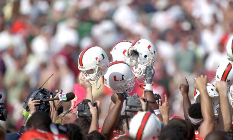 Miami football helmets held up by Hurricanes players.