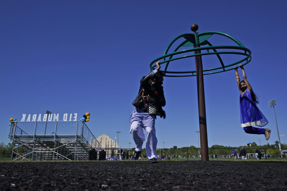 Saif Chaudhry plays with his daughter Ariana Chaudhry, 8, on playground near the site of an outdoor celebration of Eid al-Fitr in Overpeck County Park in Ridgefield Park, N.J., Thursday, May 13, 2021. Millions of Muslims across the world are marking a muted and gloomy holiday of Eid al-Fitr, the end of the fasting month of Ramadan - a usually joyous three-day celebration that has been significantly toned down as coronavirus cases soar. (AP Photo/Seth Wenig)