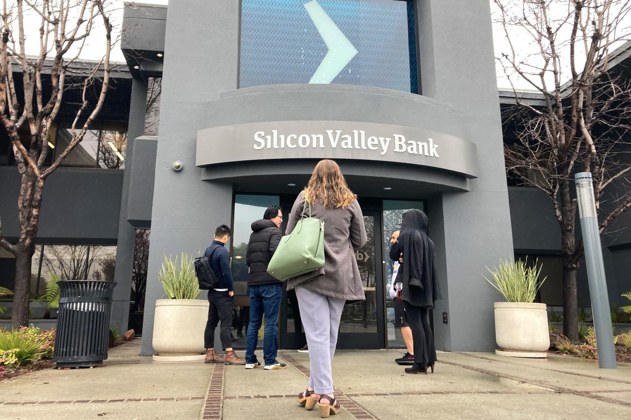 People stand outside of an entrance to Silicon Valley Bank in Santa Clara, Calif., Friday, March 10, 2023. The Federal Deposit Insurance Corporation seized the assets of the bank on Friday, marking the largest bank failure since Washington Mutual during the height of the 2008 financial crisis.