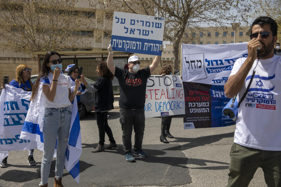 A man holds a sign, center, that reads, "Keeping Israel Jewish and democratic," during a protest by supporters of Prime Minister Benjamin Netanyahu, in front of Israel's Supreme Court, in Jerusalem, Tuesday, March 24, 2020. Israel appeared on the verge of a constitutional crisis Tuesday as top members of Benjamin Netanyahu's Likud urged their party colleague and parliament speaker to defy a Supreme Court order to hold an election for the prime minister's successor. (AP Photo/Ariel Schalit)