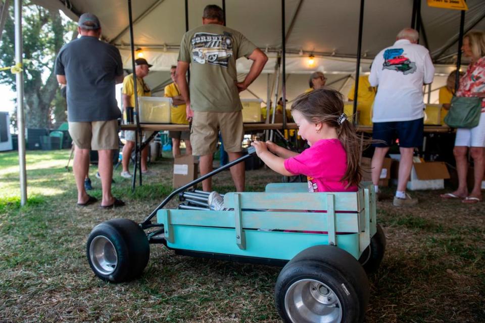 Stella Ladner, 4, plays in her toy car as her grandfather registers at Centennial Plaza during Cruisin’ the Coast on Tuesday, Oct. 3, 2023.