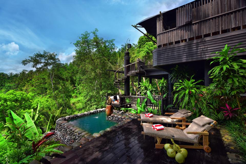 Two lounge chairs and a plunge pool overlook the jungle next to a guest room.