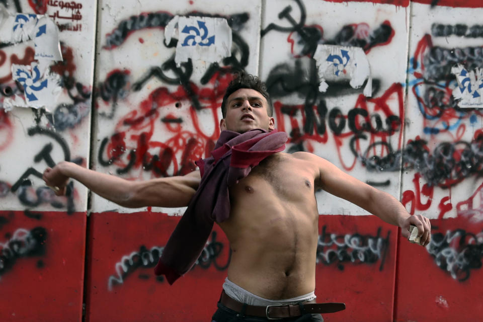 A protester throws stones towards the central bank building in Beirut, Lebanon, Saturday, March. 13, 2021. Riot police fired tear gas to disperse scores of people who protested near parliament building in central Beirut Saturday amid deteriorating economic and financial conditions and as the local currency hit new low levels (AP Photo/Bilal Hussein)