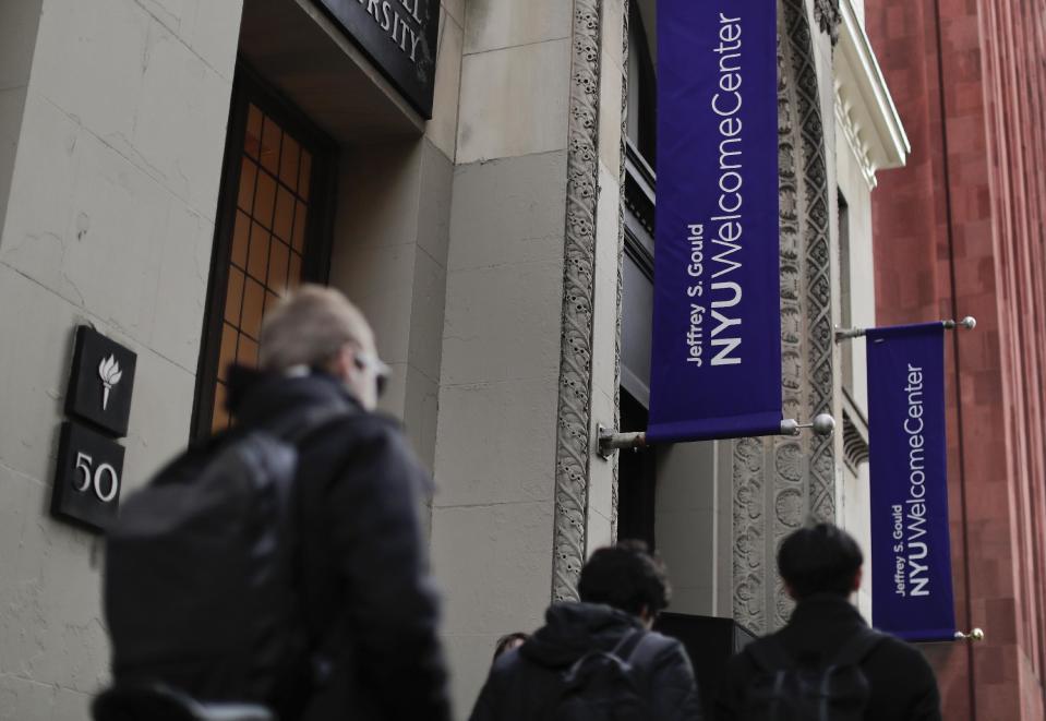 Students walk along West 4th Street in front of the Jeffrey S. Gould learning center, Wednesday, Dec. 14, 2016, in New York. New York University has introduced a program to help students save money by putting them up in elderly people's spare bedrooms. The plan has gotten serious consideration from some students straining under the institution's $66,000 annual tuition. (AP Photo/Julie Jacobson)