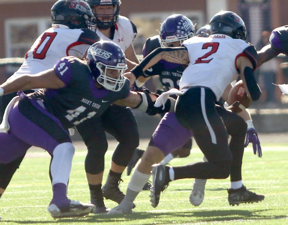 Mount Union defender Carson Kovath, left, closes in on quarterback Jordan Garrett during their home game against Muskingum Saturday, November 6, 2021 at Mount Union Stadium.