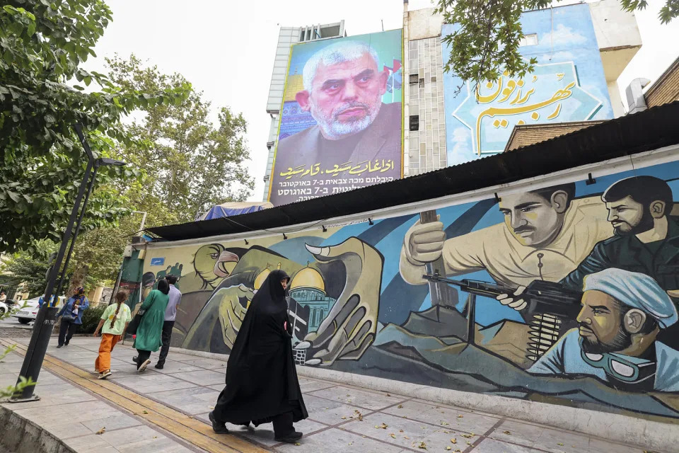 People walk past a billboard showing a portrait of newly appointed Hamas leader Yahya Sinwar in Tehran on August 12, 2024.-ISRAEL-CONFLICT (Atta Kenare / AFP - Getty Images)