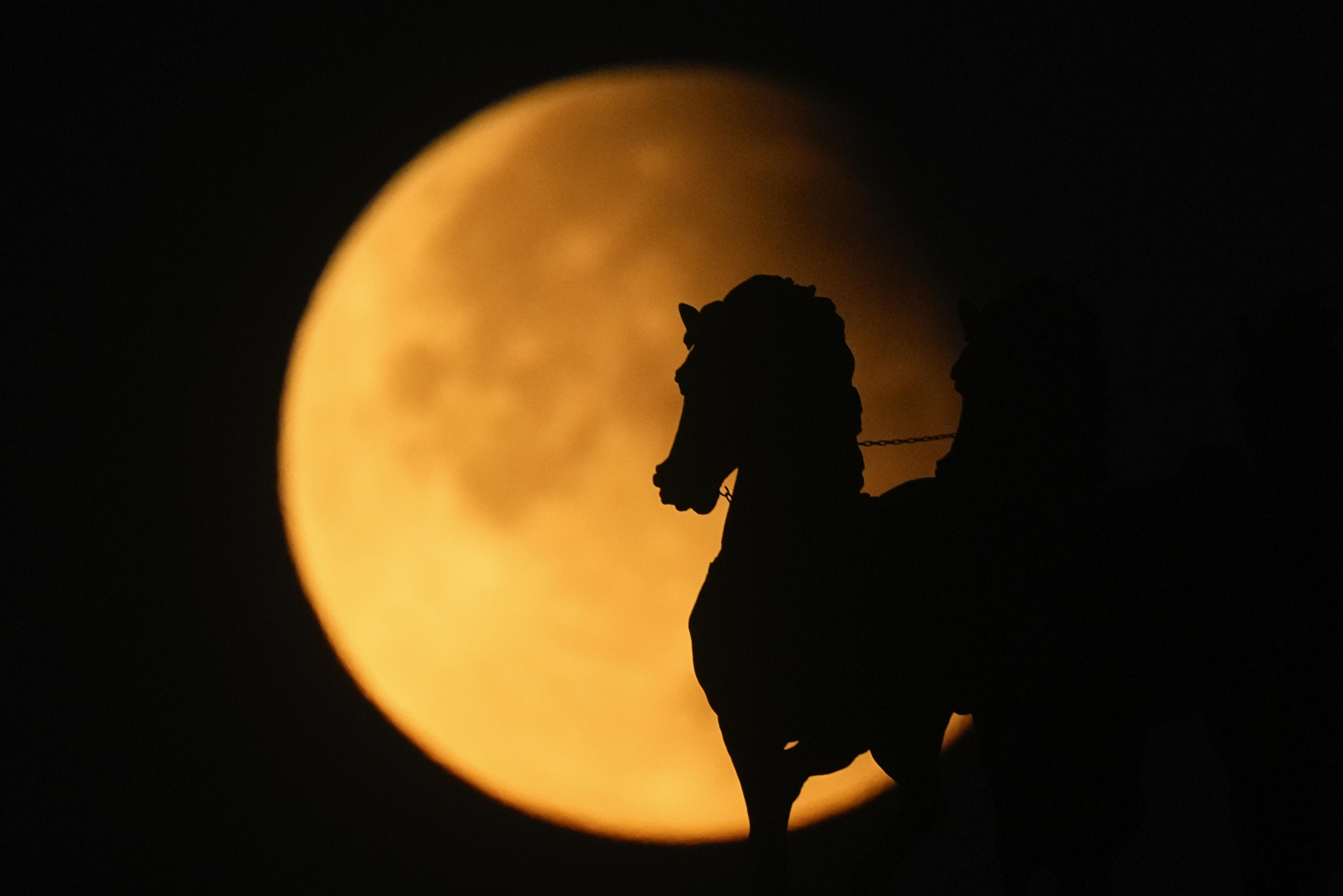 A supermoon rises behind a horse statue atop of Triumphal Arc during a partial lunar eclipse in Moscow, Russia, Sept. 18. (Pavel Bednyakov/AP)