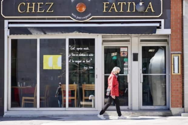 A pedestrian in a mask passes a restaurant on promenade du Portage in downtown Gatineau, Que.'s Hull community in late April 2021.  (Guillaume Lafreniere/Radio-Canada - image credit)