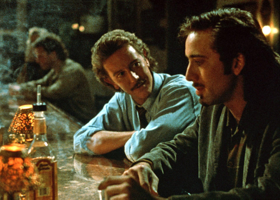 Judge Reinhold and Nicolas Cage talking at a bar.