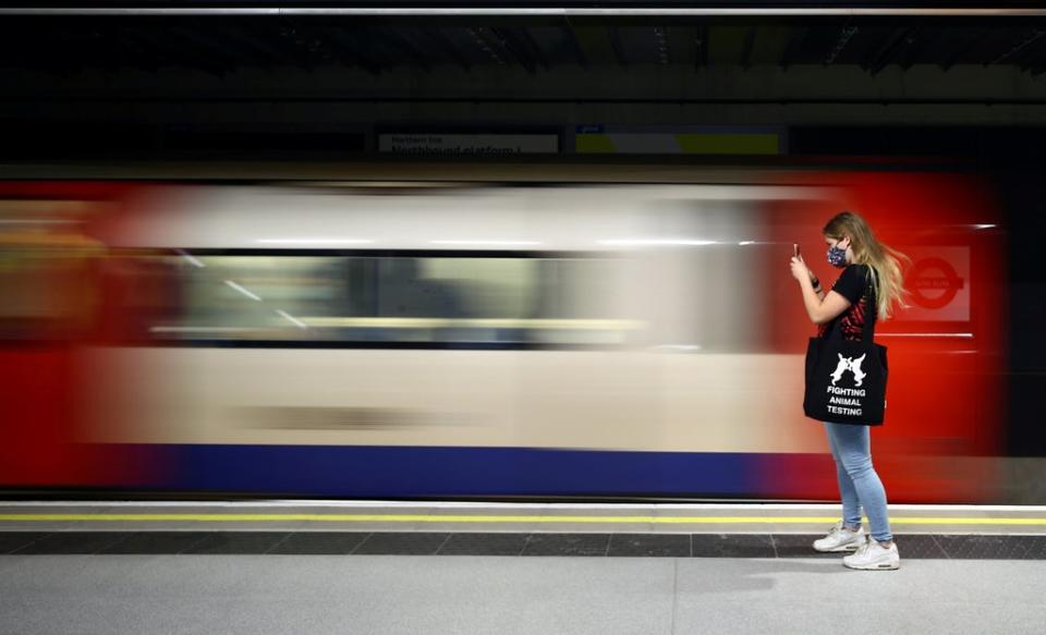 A passenger photographs the arrival of a Northern Line tube train at the newly opened Nine Elms underground station (REUTERS)