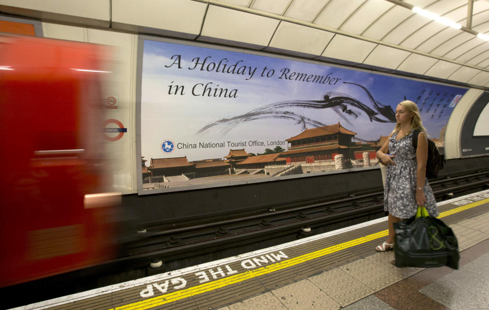 In this photo taken on Thursday, Aug. 30, 2013, a commuter waits for an incoming tube train while standing in front of a poster for the China National Tourist Office that's part of its "Beautiful China" campaign on display at the Angel tube station in Islington, London. China's new tourism slogan "Beautiful China" has been criticized by industry experts who say it illustrates a marketing problem that has led to a weakness in growth in foreign visitors over the past few years. (AP Photo/Alastair Grant)