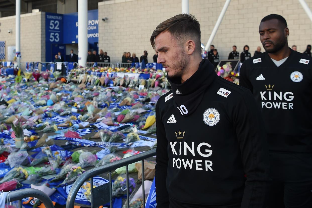 English midfielder James Maddison (L) and Leicester City’s English-born Jamaican defender Wes Morgan (R) look at the floral tributes (Photo by Mike Egerton/PA Images via Getty Images)