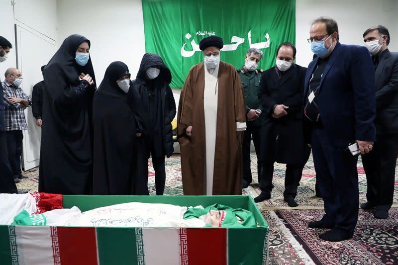 FILE PHOTO: Ebrahim Raisi, head of Iran's judiciary, and family members of Iranian nuclear scientist Mohsen Fakhrizadeh, stand next to his body in Tehran