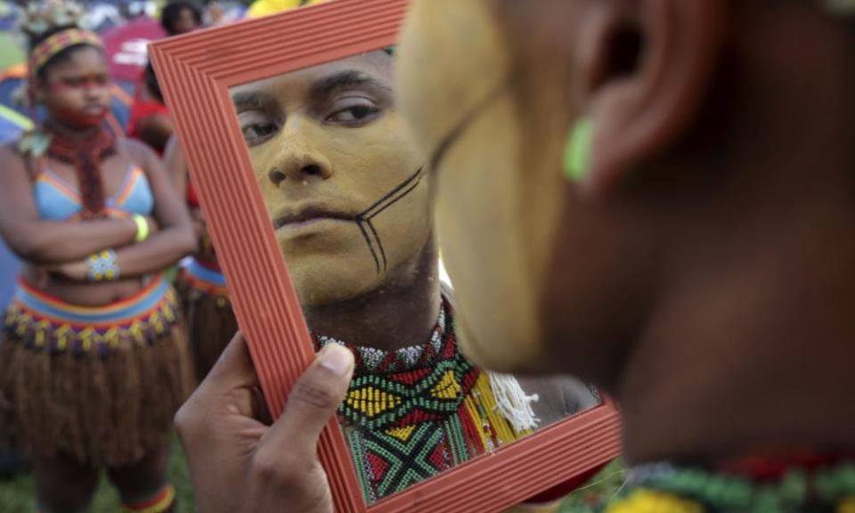 A young indigenous man applies body paint in Brasília.