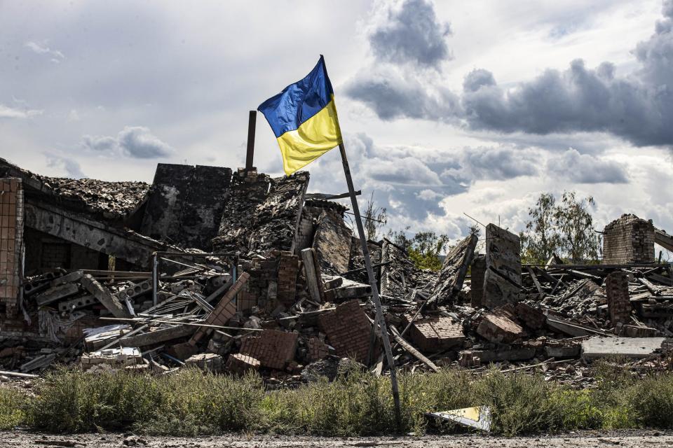 A Ukrainian flag in a heavily damaged area a recently liberated town