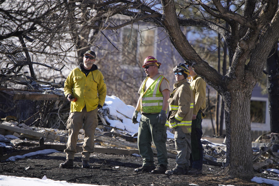 U.S. Forest Service employees join firefighters in assessing the remains of trees and homes destroyed by wildfires Tuesday, Jan. 4, 2022, in Superior, Colo. (AP Photo/David Zalubowski)