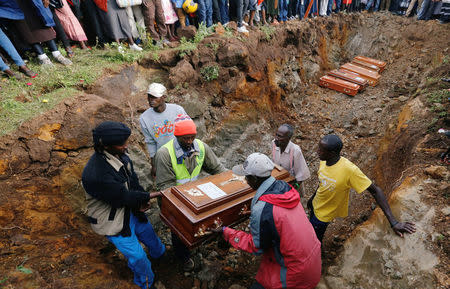 Relatives arrange the coffins of their kin inside a mass grave during the burial of people killed when a dam burst its walls, overrunning nearby homes, in Solai town near Nakuru, Kenya May 16, 2018. REUTERS/Thomas Mukoya