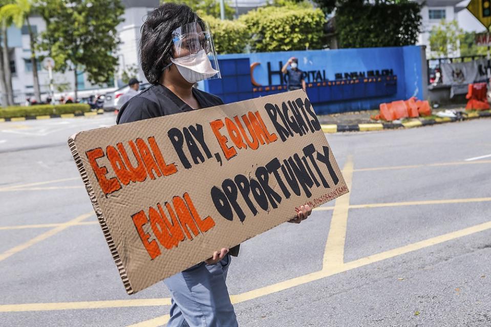 A contract doctor holds aloft a placard demanding equal treatment during a strike at the Sungai Buloh Hospital July 26, 2021. — Picture by Hari Anggara