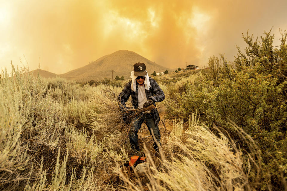 David Garfield clears a fire break around his home as the Sugar Fire, part of the Beckwourth Complex Fire, burns towards Doyle, Calif., on Saturday, July 10, 2021. (AP Photo/Noah Berger)