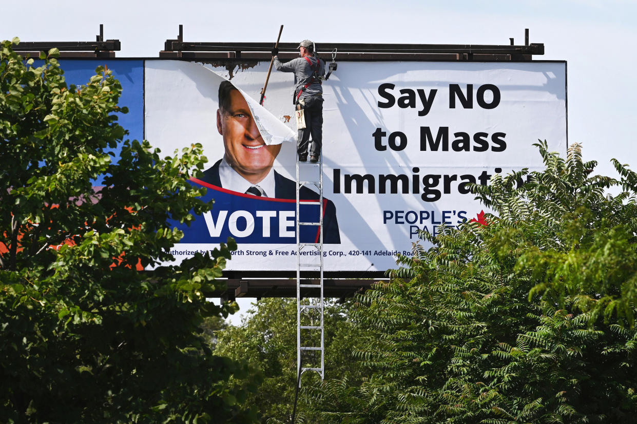 A worker removes a billboard featuring the portrait of People’s Party of Canada (PPC) leader Maxime Bernier and its message "Say NO to Mass Immigration" in Toronto, Ontario, Canada August 26, 2019.  REUTERS/Moe Doiron