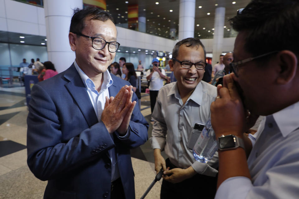 CORRECTS LOCATION - Cambodia's exiled opposition leader Sam Rainsy, left, greets supporters as he arrived at Kuala Lumpur International's Airport in Sepang, Malaysia Saturday, Nov. 9, 2019. Sam Rainsy landed in Kuala Lumpur in a bid to return to his homeland after Thailand had earlier blocked him from entering. (AP Photo/Vincent Thian)