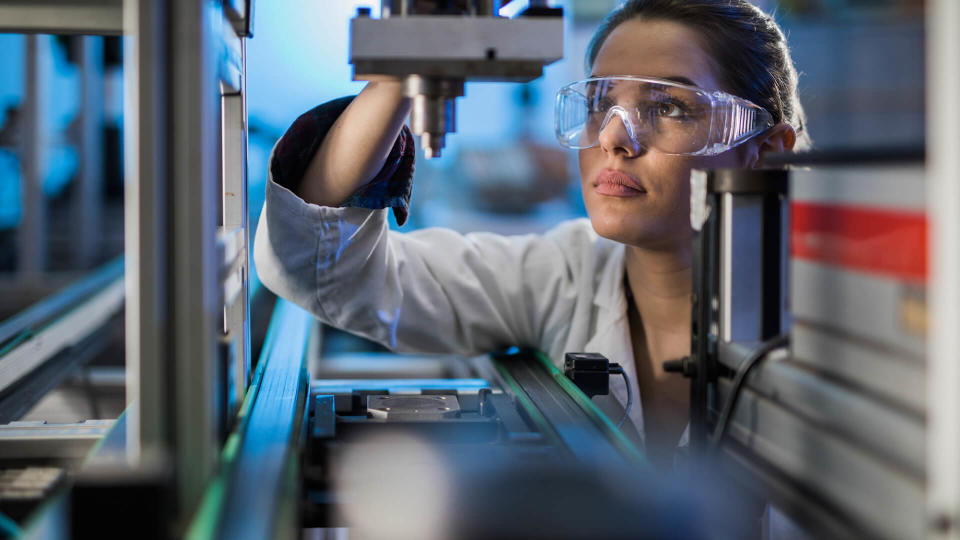 Quality control worker analyzing machine part on a manufacturing machine.