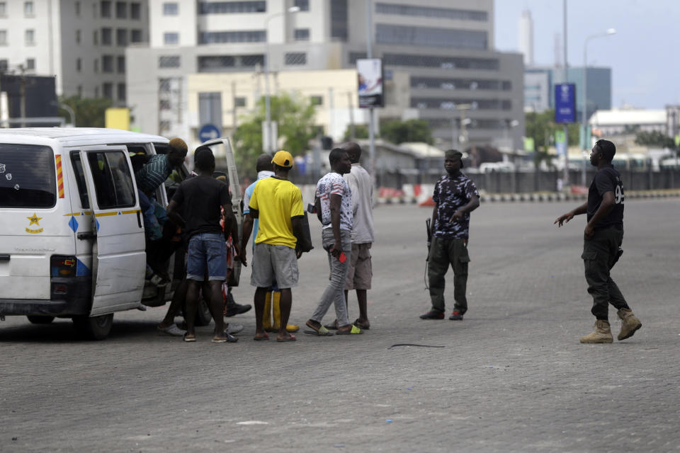 Police officers stop and search a bus carrying passengers around Lekki toll gate in Lagos Friday, Oct. 23, 2020. Resentment lingered with the smell of charred tires Friday as Nigeria's streets were relatively calm after days of protests over police abuses, while authorities gave little acknowledgement to reports of the military killing at least 12 peaceful demonstrators earlier this week. (AP Photo/Sunday Alamba)