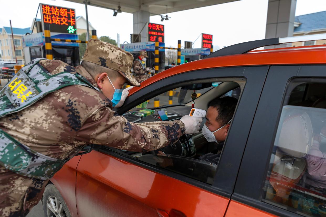 A militia member uses a digital thermometer to take a driver's temperature at a checkpoint at a highway toll gate in Wuhan in central China's Hubei Province, Thursday, Jan. 23, 2020. China closed off a city of more than 11 million people Thursday in an unprecedented effort to try to contain a deadly new viral illness that has sickened hundreds and spread to other cities and countries amid the Lunar New Year travel rush. (Chinatopix via AP)