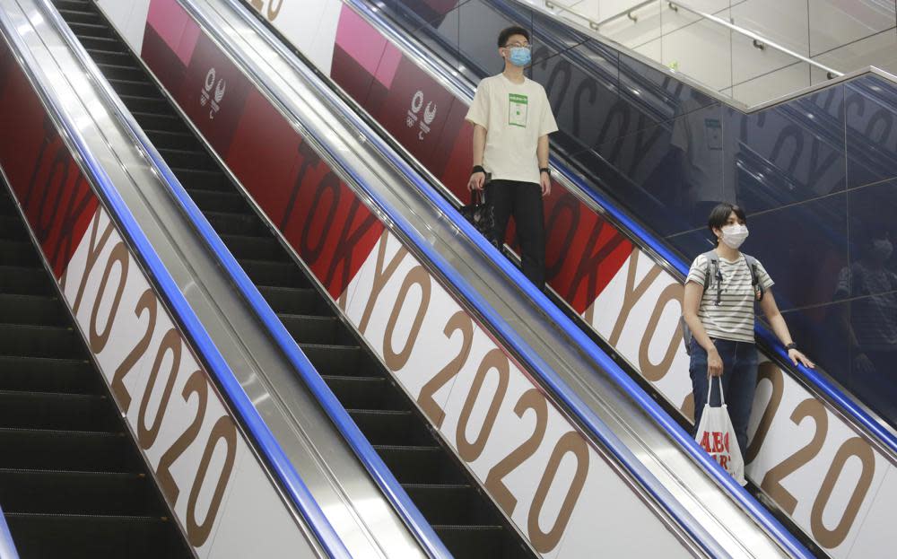 In this July 7, 2021, file photo, people wearing face masks ride an escalator with banners to promote the Tokyo Olympics scheduled to open on July 23, in Tokyo. (AP Photo/Koji Sasahara, File)