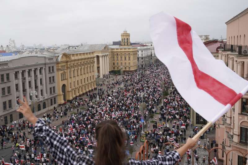 8月23日，大批白羅斯民眾在首都明斯克的獨立廣場示威抗議。一名女子在高處揮舞著抗議的旗幟（美聯社）