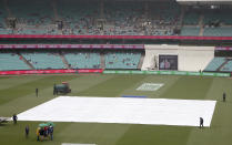 Rain falls as the pitch is covered during a delay before play on day 5 of the cricket test match between India and Australia in Sydney, Monday, Jan. 7, 2019. (AP Photo/Rick Rycroft)