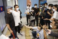 Pyae Lyan Aung, second from left, a member of the Myanmar national Olympic team who raised a three-finger salute during a qualifying match for the 2022 World Cup in late May, speaks to media as he arrives at the Kansai International Airport in Osaka Prefecture, Japan, Thursday June 17, 2021. Pyae Lyan Aung has refused to return home and is seeking asylum, a request the government was considering taking into account unrest in his country following a coup.(Kyodo News via AP)