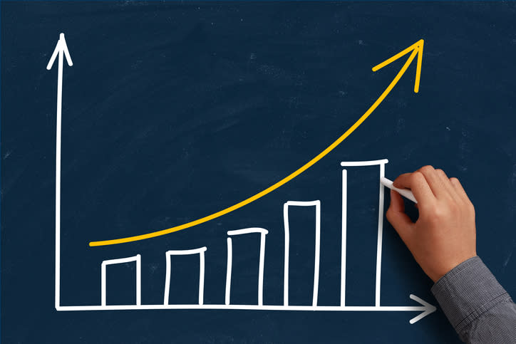 A hand drawing an ascending bar chart on a chalkboard.