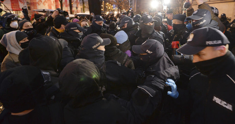 Police confront protesters in front of the Education Ministry building in Warsaw, Poland, on Monday Nov. 23, 2020. Police detained several people as women-led protests over abortion rights flared up in Warsaw and elsewhere in Poland. The protests, organized by the group Women's Strike, have been occurring regularly since the constitutional court issued an Oct. 22 ruling that further tightens an abortion law that was already one of the most restrictive in Poland.(AP Photo/Czarek Sokolowski)