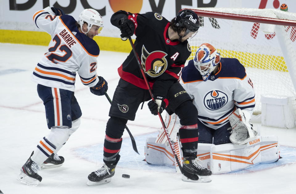 Ottawa Senators left wing Nick Paul tries to deflect the puck under pressure from Edmonton Oilers defenseman Tyson Barrie as goaltender Mikko Koskinen stays focused during the first period of an NHL hockey game Wednesday, April 7, 2021, in Ottawa, Ontario. (Adrian Wyld/The Canadian Press via AP)