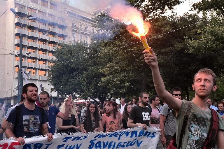 A demonstrator holds up a a flare as students participate in a rally against the EU-IMF loan deal in central Athens on June 11, 2015