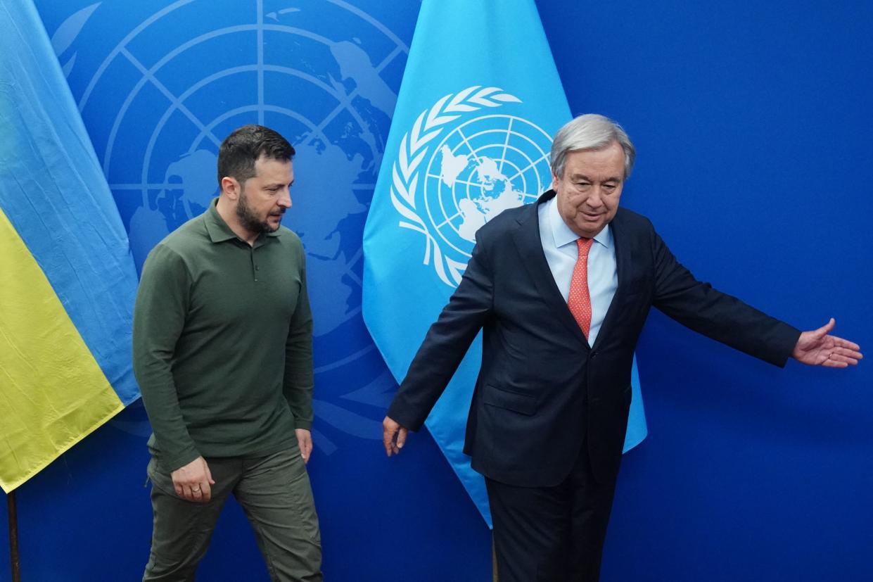 Zelensky walks with United Nations Secretary-General António Guterres. The flags of Ukraine and the United Nations are behind them.