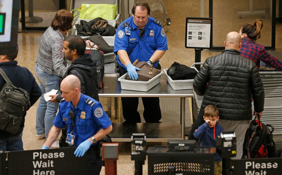 A TSA worker helps passengers at the Salt Lake City International Airport, Wednesday, Jan. 16, 2019, in Salt Lake City. The government shutdown has generated an outpouring of generosity to TSA agents and other federal employees who are working without pay. In Salt Lake City, airport officials treated workers from the TSA, FAA and Customs and Border Protection to a free barbecue lunch as a gesture to keep their spirits up during a difficult time.