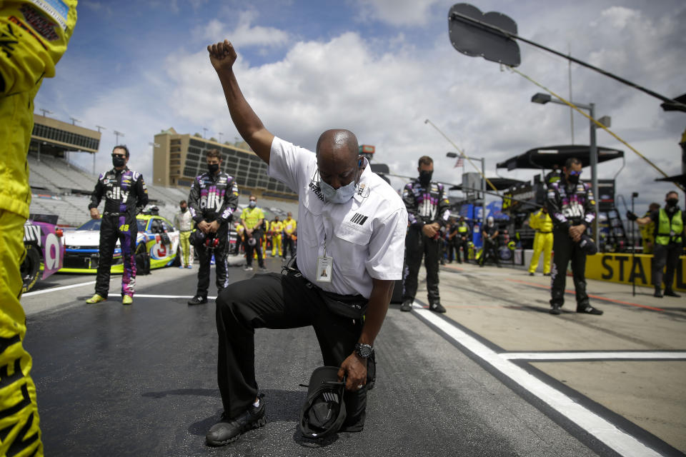 A NASCAR official kneels during the national anthem before a NASCAR Cup Series auto race at Atlanta Motor Speedway, Sunday, June 7, 2020, in Hampton, Ga. NASCAR paused before Sunday’s Cup race at Atlanta Motor Speedway to acknowledge the country’s social unrest. (AP Photo/Brynn Anderson)