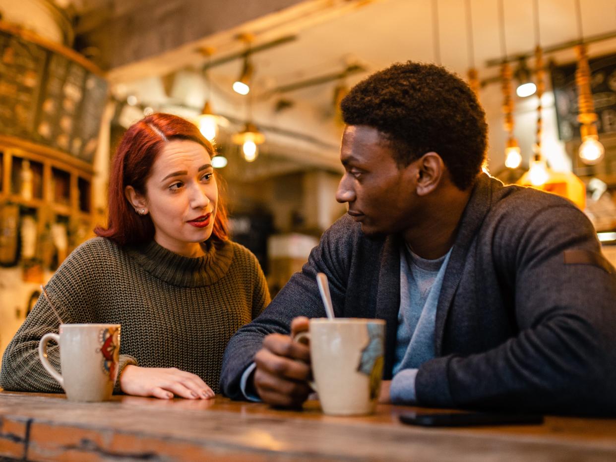 Two people have a serious discussion over coffee at a cafe.