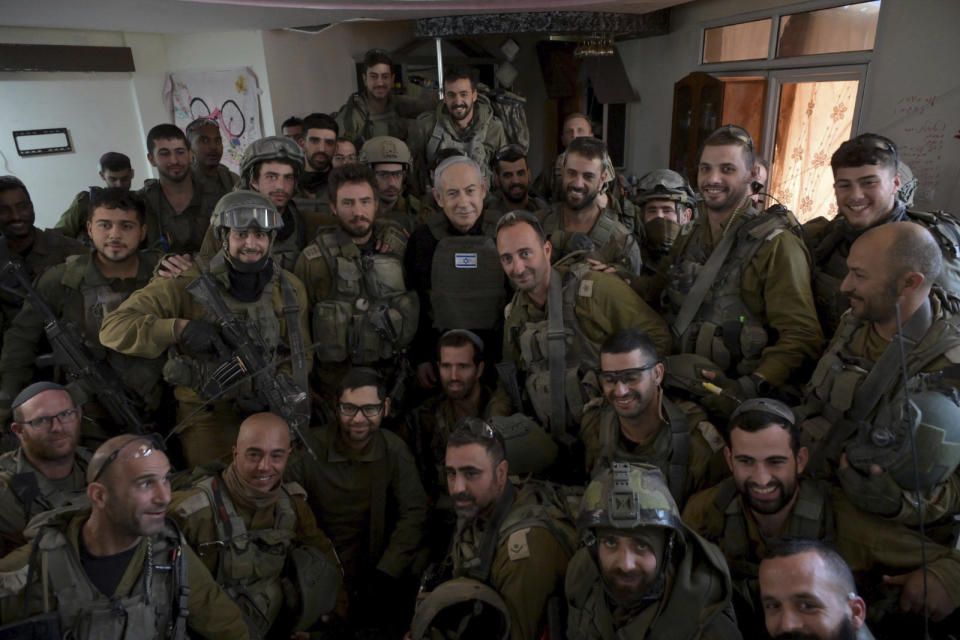 Israeli Prime Minister Benjamin Netanyahu, center, poses for a photo with Israeli soldiers in the northern Gaza Strip, on Monday, Dec. 25, 2023. (Avi Ohayon/GPO/Handout via AP)
