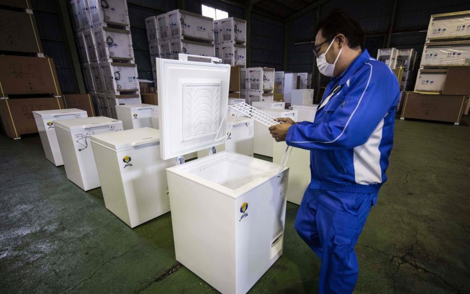 Masahiko Nakayama, a manager at fridge manufacturer Kanou Reiki, shows a deep freezer which will be used to store COVID-19 coronavirus vaccines, at the company warehouse in Sagamihara